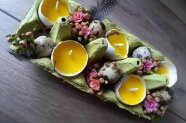 Eierschachtel mit gelben Eierkerzen und Dekoration