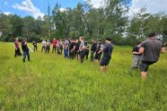 Personen stehen auf einer Wiese mit hohem Gras