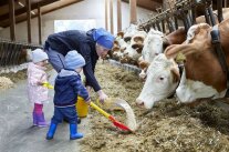 Frau steht zusammen mit zwei kleinen Kindern im Stall