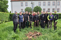 Personengruppe auf einer Wiese vor Gebäude