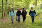Vier Kinder die lachend durch den Wald gehen