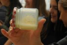 Eine Hand hält ein Einmachglas, in dem ein Stück Butter ist