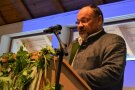 Mann steht am Mikrofon und hält eine Rede