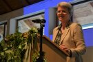 Frau steht am Mikrofon und hält eine Rede