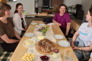Frauen sitzen um einen gedeckten Tisch mit Brot und Butter